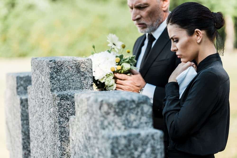 man and woman visiting a grave stone