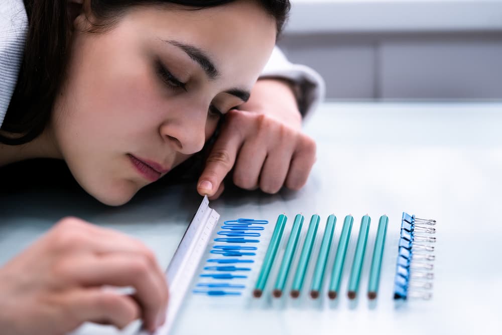 woman lining up paperclips, pencils, and binder clips